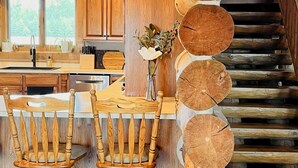 A wooden staircase with a rustic design, a kitchen area with wooden cabinets and a sink, and two wooden chairs with a vase of flowers on the table. - Foote Creek Lodge (Aberdeen)