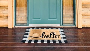 A wooden cabin with a teal door, a wreath, and a 'hello' mat. - Foote Creek Lodge (Aberdeen)