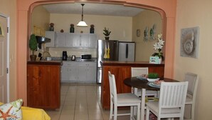 A kitchen with a central island, white chairs, and a dining table.