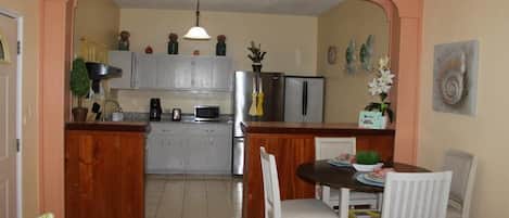 A kitchen with a central island, white chairs, and a dining table.