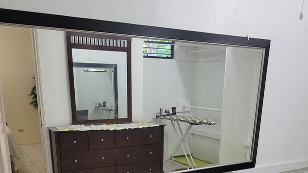 A room with a large mirror, a dresser, and a window.