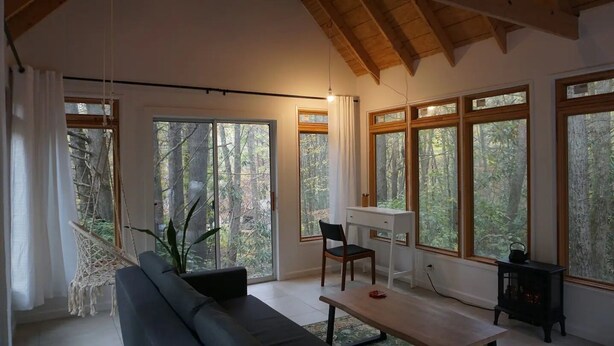 A spacious living area with a large window, a sofa, a table, and a desk. - Cozy cabin in the Cherokee National Forest. (Del Rio)