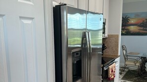 A stainless steel refrigerator in a kitchen with white cabinetry and a tiled floor.