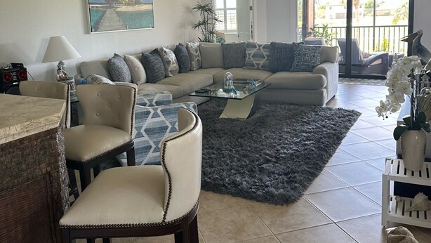 A living room with a sofa, chairs, a coffee table, and a ceiling fan.