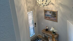 A staircase with a wooden handrail leading to a landing with a decorative light fixture and a framed painting.