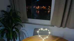 A round wooden table with a heart-shaped light fixture in the center, surrounded by chairs. - Rheinromantik mit Blick auf die Burg Katz, bis 4P (Sankt Goar)