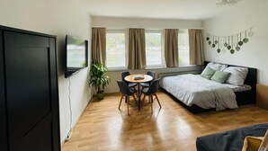 A compact room with a bed, a TV, a dining table with chairs, and a potted plant. - Rheinromantik mit Blick auf die Burg Katz, bis 4P (Sankt Goar)