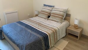 Un dormitorio con una cama, dos mesitas de noche, una lámpara y una obra de arte en la pared.