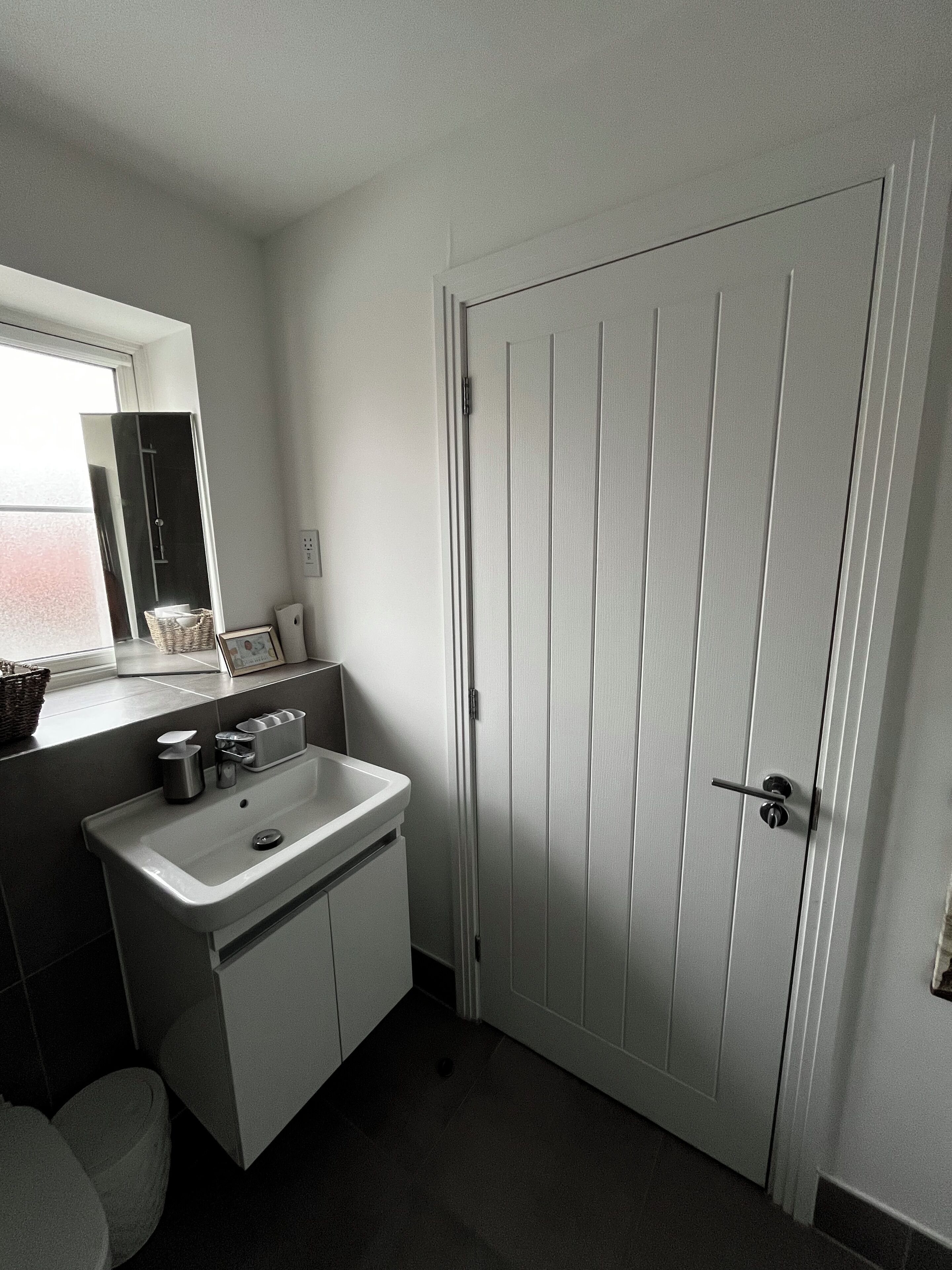 A bathroom with a sink, mirror, and a white door.
