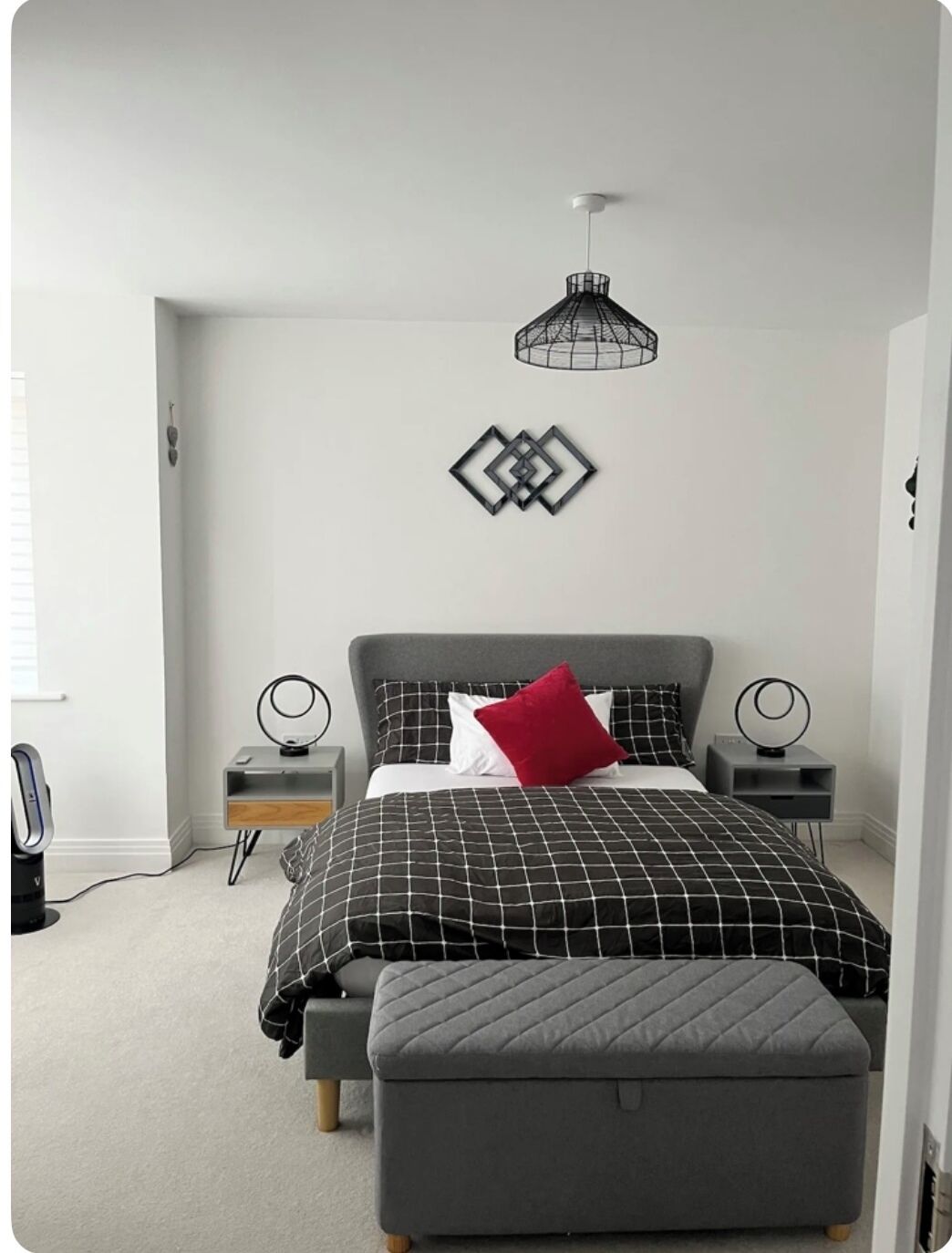 A bedroom with a bed, bedside tables, a desk, and a pendant light.