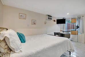 Ein Hotelzimmer mit Bett, Schreibtisch, Fernseher und einem Fenster mit Vorhängen.