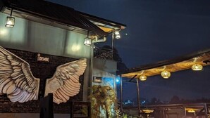 A building with a large winged sculpture on the wall, a sign reading "DEMBE", and a moon in the sky. - Idembe Heritage (Nyamabuye)