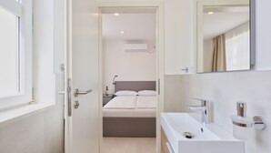 Un baño moderno con un lavamanos blanco, un espejo y una ducha.