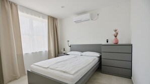 Un dormitorio moderno con cama, mesita de noche, cómoda y aire acondicionado.