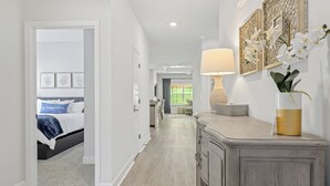 A hallway with a bed, a dresser, and a lamp. - Fully-Fenced Backyard! Perfect for Families/Groups (Tallahassee)