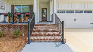 A two-story house with a front porch, a garage, and a brick staircase. - Fully-Fenced Backyard! Perfect for Families/Groups (Tallahassee)
