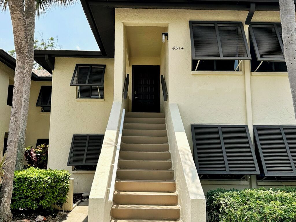 A beige building with a staircase leading to a black door, number 4514.