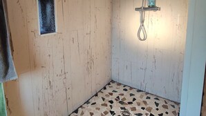 A small, rustic bathroom with a shower, a tiled floor, and a towel hanging on the wall. - Bel Appartement, au Calme. Animaux de Compagnie Acceptés ! (Corbère-les-Cabanes)