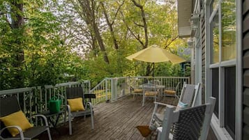 Relax on the deck surrounded by lush greenery, with a table and chairs for al fresco dining.