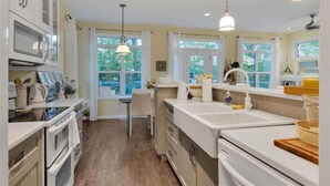 Una cocina moderna con armarios blancos, una isla central e iluminación colgante.