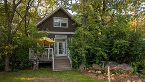 A two-story wooden house with a front porch and a covered patio area.