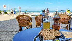 Una mesa con una botella de Blanche de Narbonne, un vaso de bebida amarilla y rebanadas de pan.