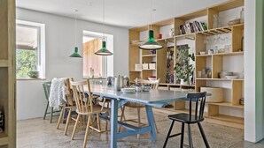Un espace repas avec une table bleue, des chaises en bois et des suspensions vertes.