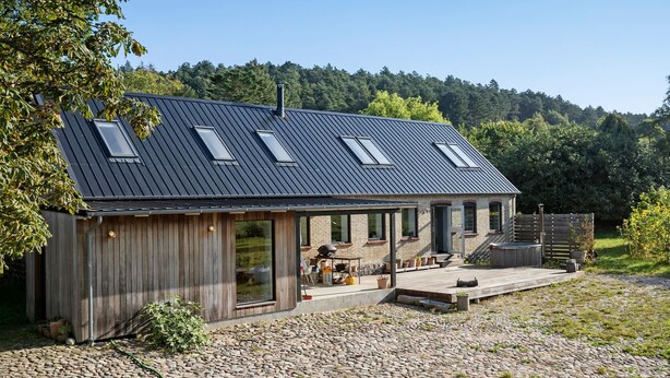 Une maison moderne avec un toit en pente, de grandes fenêtres et un espace patio.