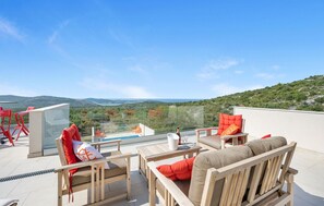 A rooftop terrace with a pool, red and beige outdoor furniture, and a scenic view of hills and water. - Lovely home in Jarebinjak (Jarebinjak)