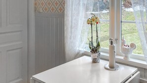 A white table with a potted plant and a candle holder by a window with lace curtains. - 2 bedroom nice home in Mariannelund (Mariannelund)