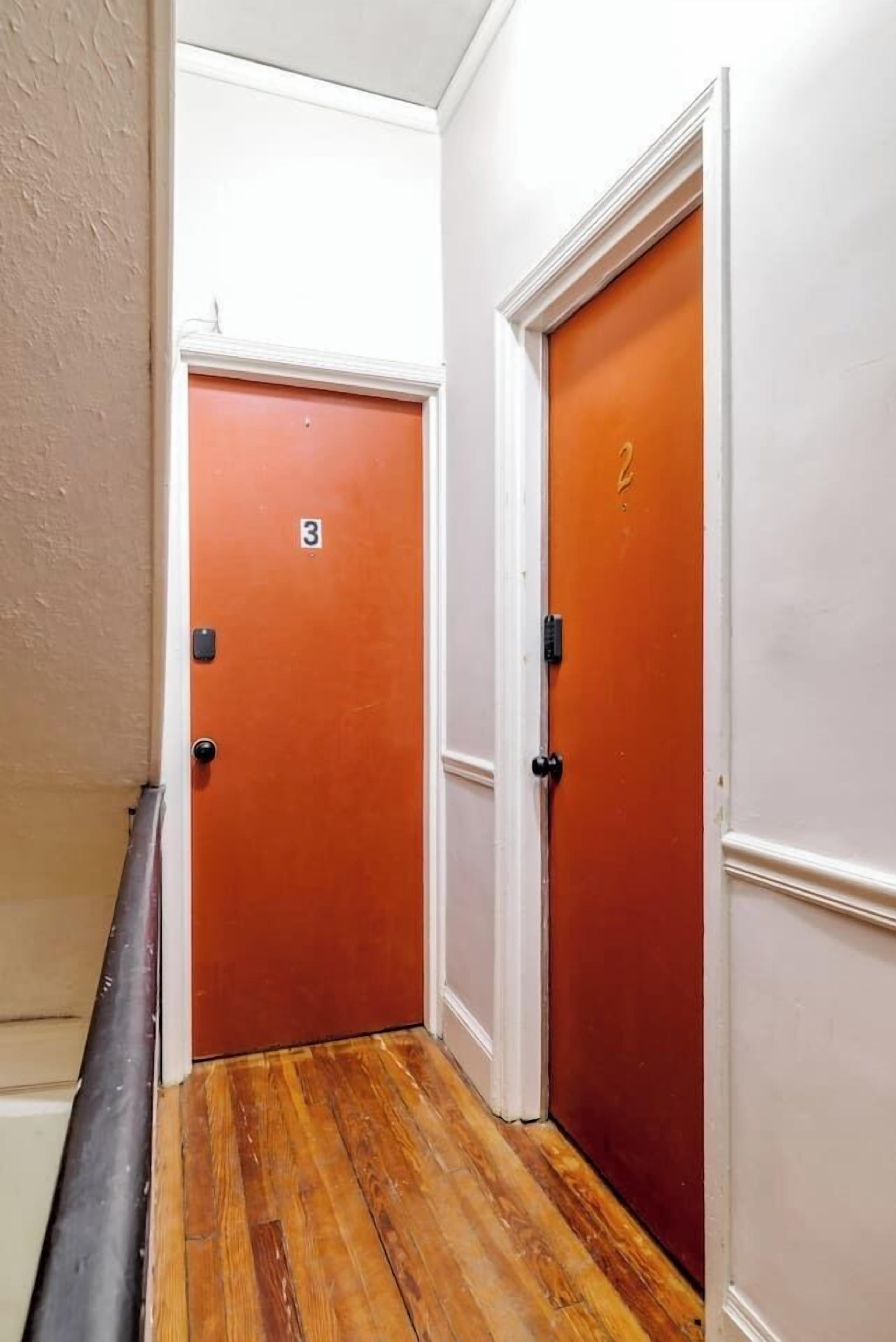 A narrow hallway with wooden flooring and two doors, one marked with the number 3 and the other with the number 2.