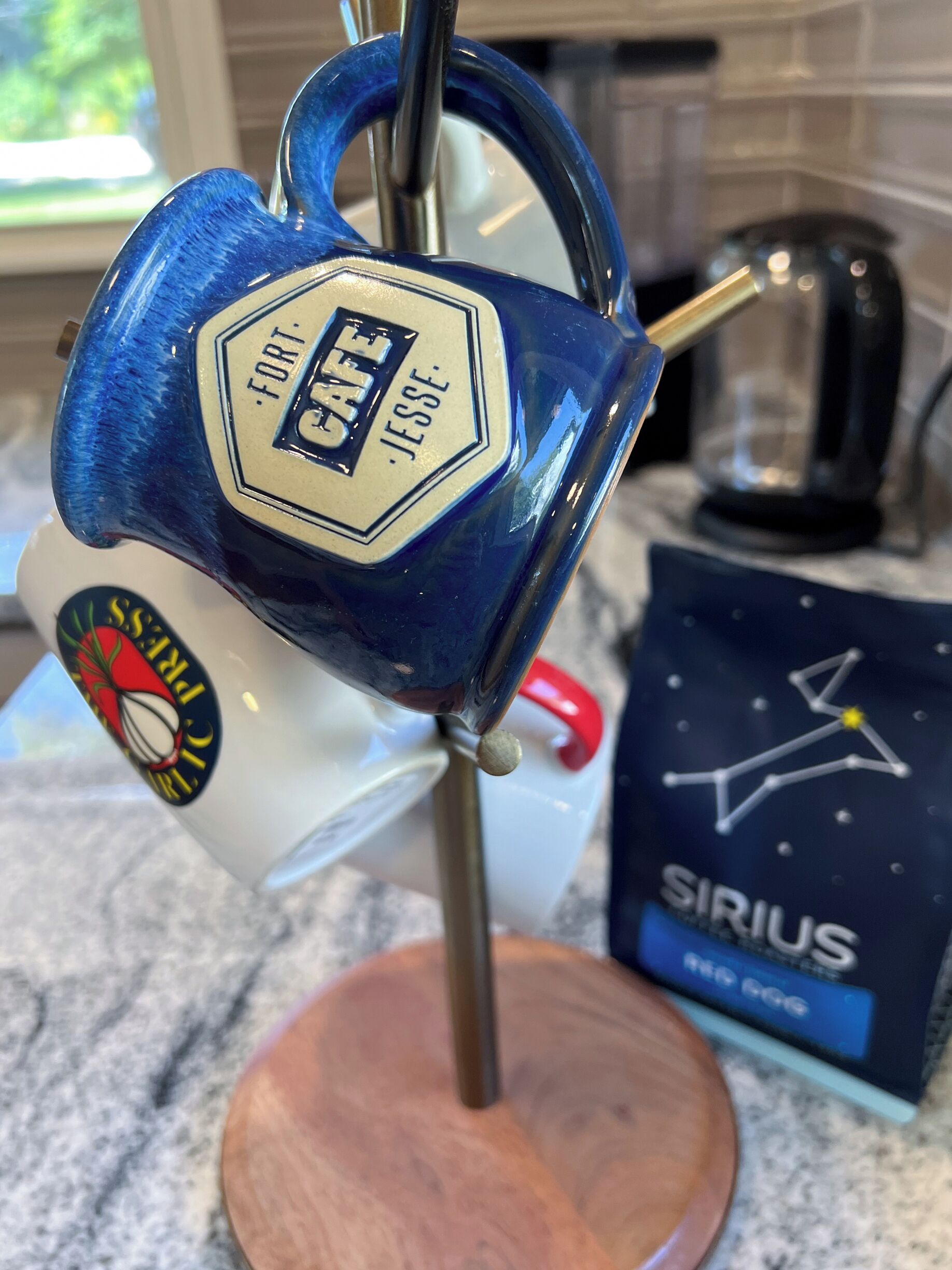 Une tasse bleue avec une étiquette portant l’inscription « FORT. JESSIE » et un logo sur l’anse.