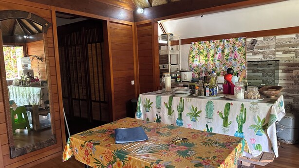Una cocina con armarios de madera, una mesa de comedor con mantel floral y una encimera con diversos objetos.