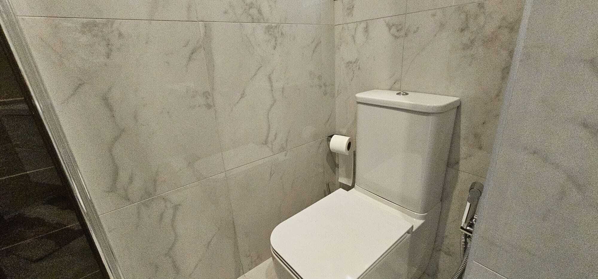 Un baño pequeño y cerrado con un inodoro y un dispensador de papel higiénico.