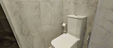 Un baño pequeño y cerrado con un inodoro y un dispensador de papel higiénico.