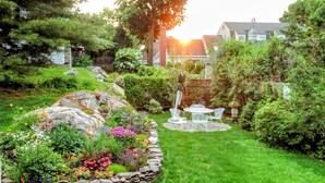 A well-maintained garden with a stone border, a patio table, and chairs. - Cozy Seaside studio in charming Marblehead with AC, WiFi. Short walk to downtown (Marblehead)