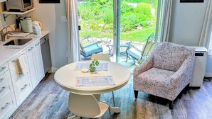 A modern kitchen with a dining area, a large window, and a view of the garden. - Cozy Seaside studio in charming Marblehead with AC, WiFi. Short walk to downtown (Marblehead)