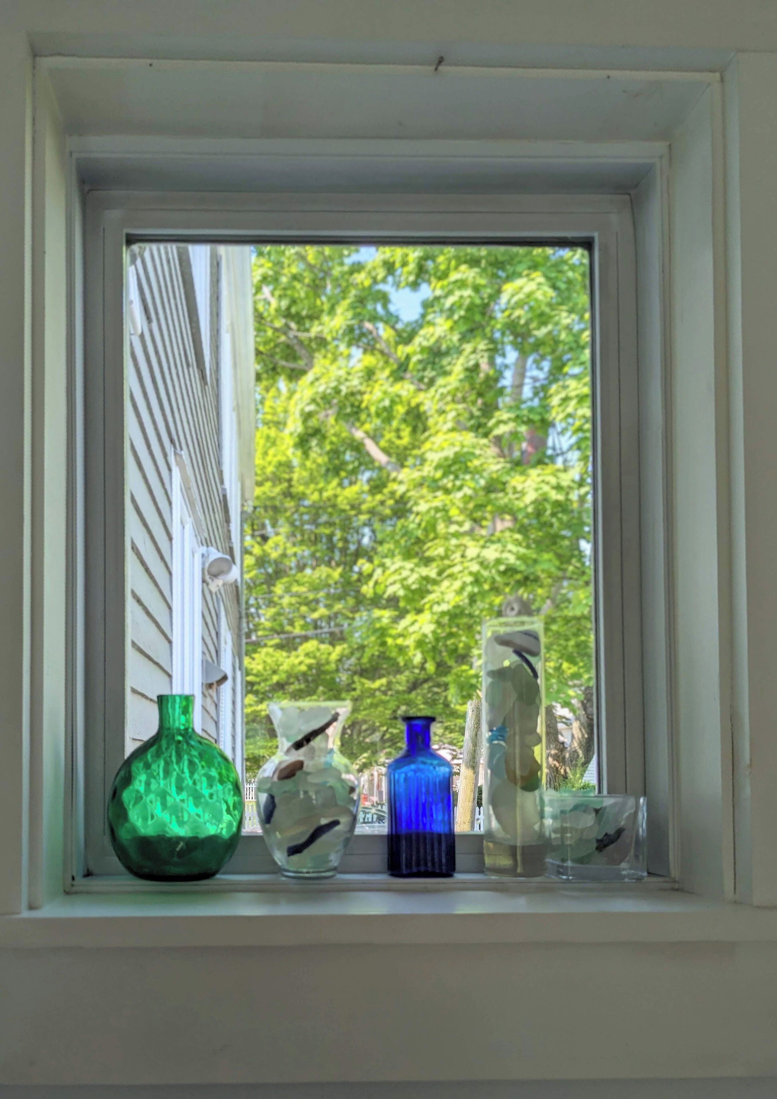 A window with various glass objects on the sill.