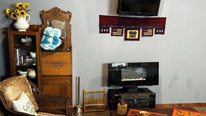 A living room with a television, a bookshelf, a wicker chair, a leather sofa, and a chessboard. - Cozy studio in enjoyable Gypsum with AC, WiFi (Gypsum)