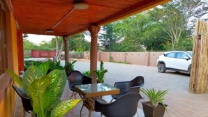 Une terrasse extérieure avec une table et des chaises, entourée de plantes en pot.