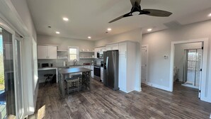 A modern kitchen with white cabinets, a stainless steel refrigerator, and a ceiling fan. - Secluded New Cottage, Minutes From Sunset Marina Overlooking Pendergrass Creek (Byrdstown)