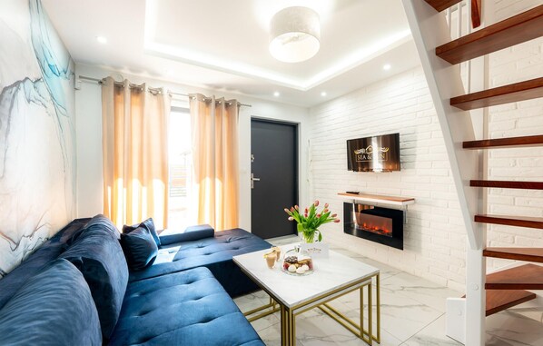Cozy up by the fireplace in this inviting living room, featuring a comfortable sofa, a small table, and a mounted TV.