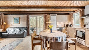 Interior acollidor d'una cabana amb zona de menjador, sofà i cuina.