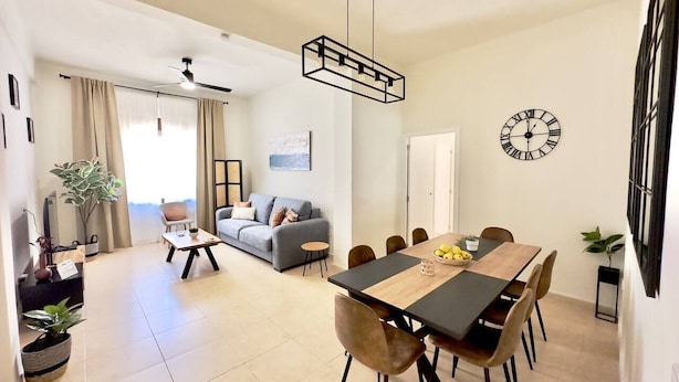 Una sala de estar moderna con comedor, un sofá, una mesa de centro y una mesa de comedor con sillas.
