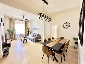 Una sala de estar moderna con comedor, un sofá, una mesa de centro y una mesa de comedor con sillas.