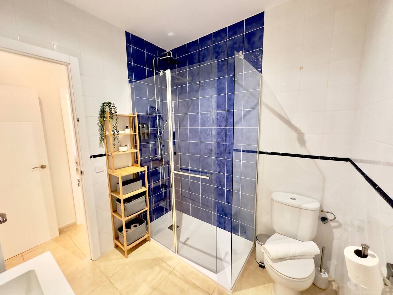 Ein Badezimmer mit Glasdusche, Toilette und Ablage mit Boxen.