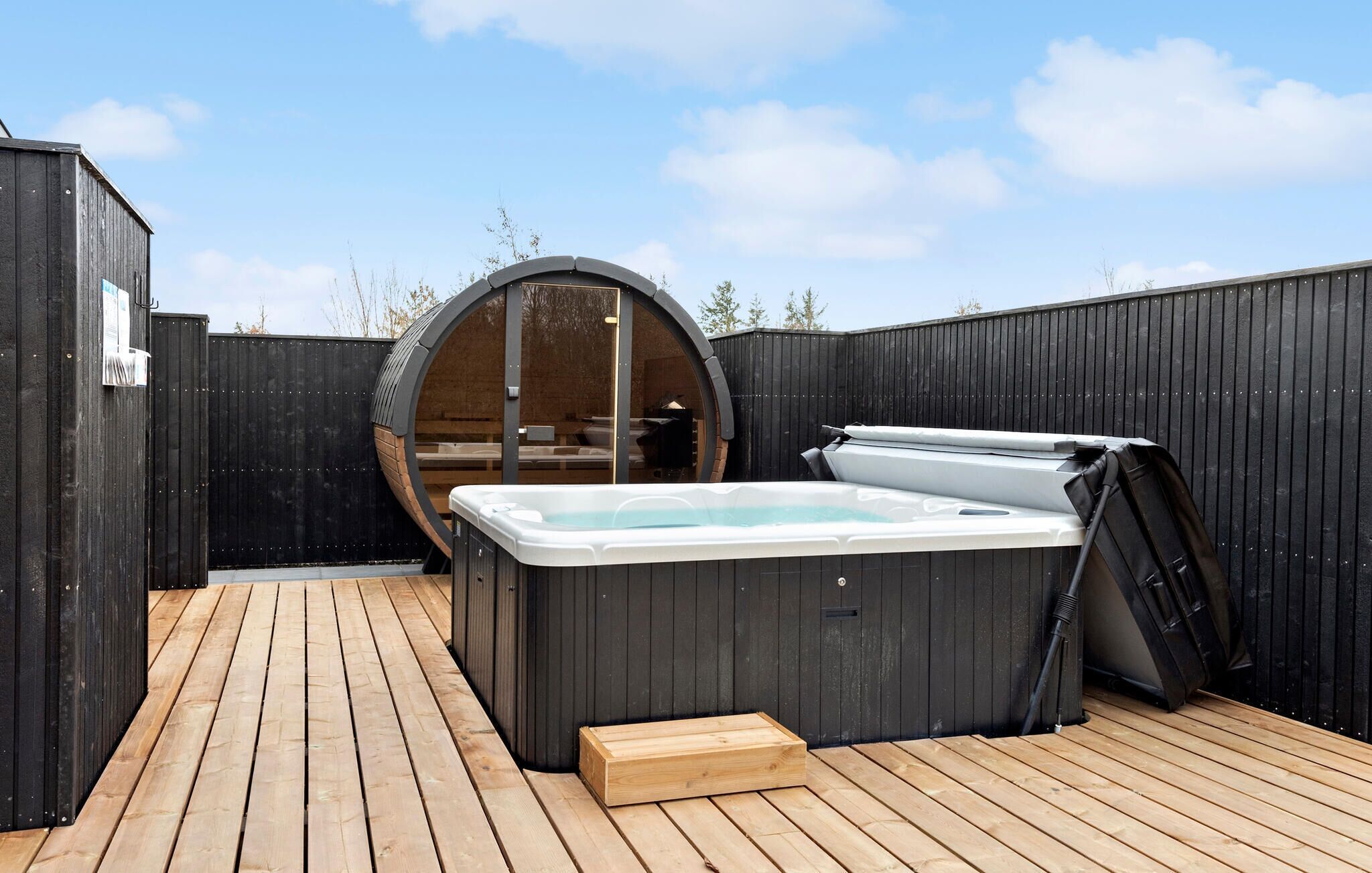 A hot tub in a wooden deck area with a wooden fence surrounding it.