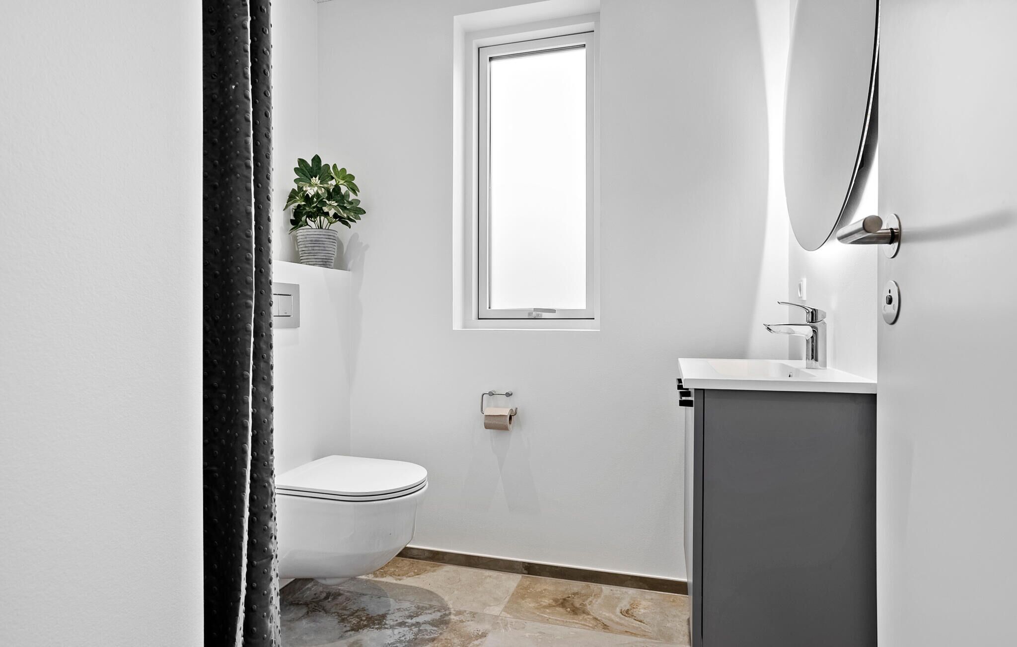 Un bagno piccolo e moderno con il water, un lavandino e una finestra.