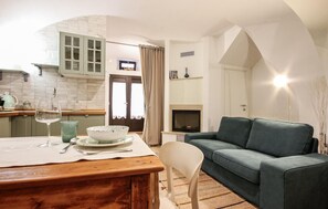 Ein gemütliches Wohnzimmer mit einem grünen Sofa, einem Esstisch mit Schüssel und Weinglas sowie einem Kamin.