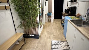 A modern kitchen with a wooden bench, a potted plant, a blue chair, and a patterned rug. - Scilló House (Palermo)